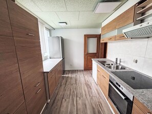 Eine Küche mit Holzausstattung, einer Edelstahl-Spüle und einem eingebauten Backofen.