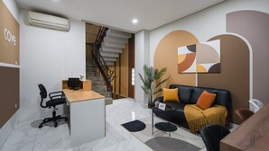 A modern office space with a reception desk, a staircase, and a living area with a sofa and coffee table.