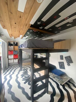 Un letto a castello con un tappeto a motivi zebrati, un soffitto decorato con stelle e una parete con cornici.