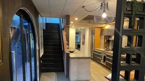 A modern interior with a staircase leading to upper floors, a kitchen area, and a seating area with a unique black partition. - Electric Beach Home. (Bowentown)