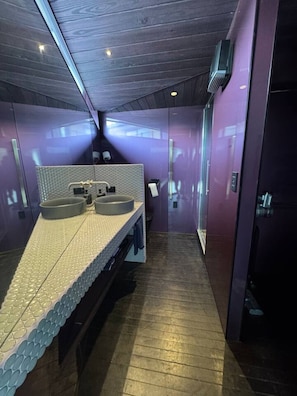 Un bagno moderno con una lunga panca, due lavabi e uno specchio.