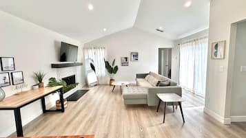 A modern living room with a fireplace, a sofa, a coffee table, and a TV mounted on the wall.