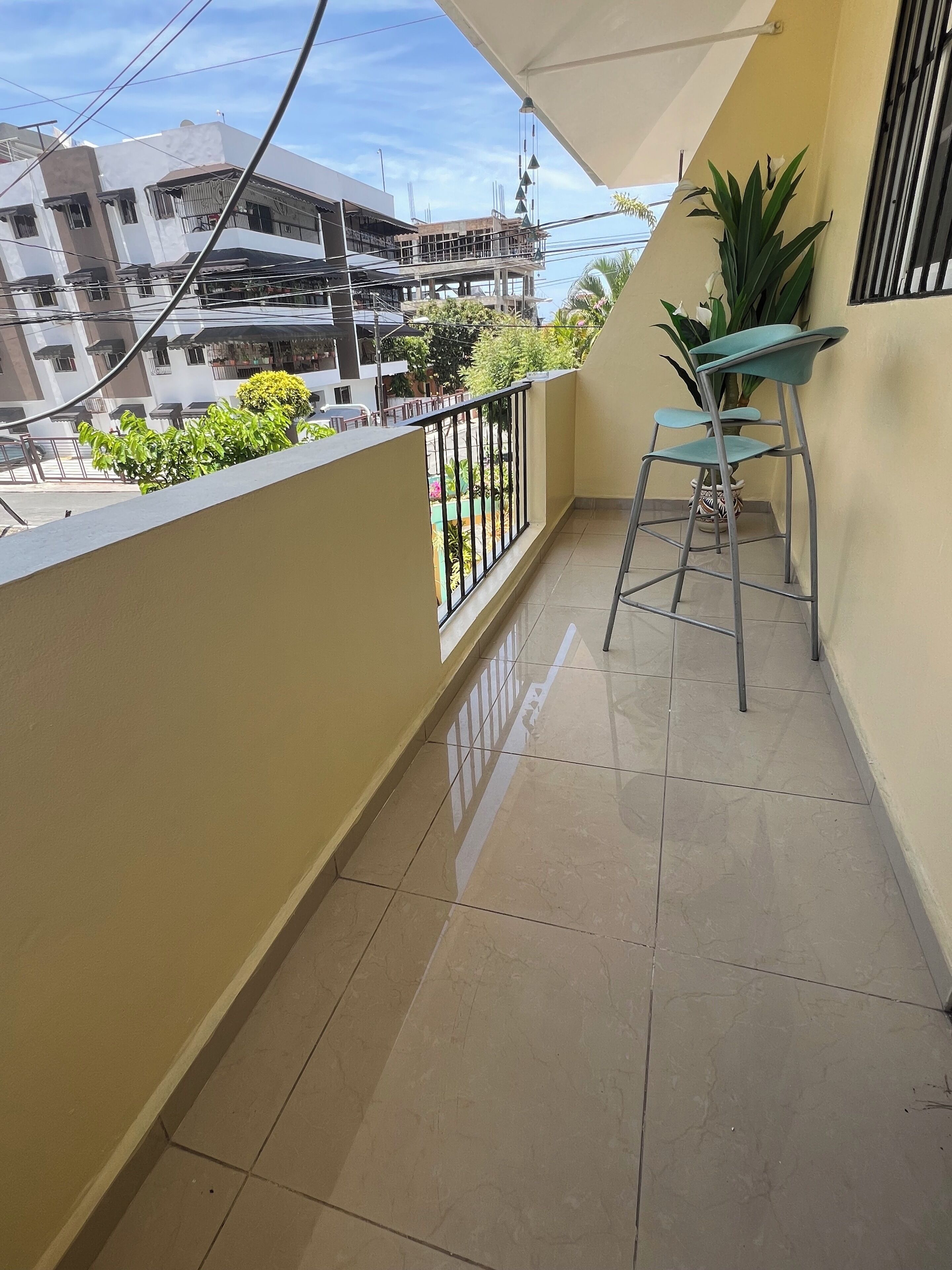 A balcony with a tiled floor, a metal chair, and a potted plant.