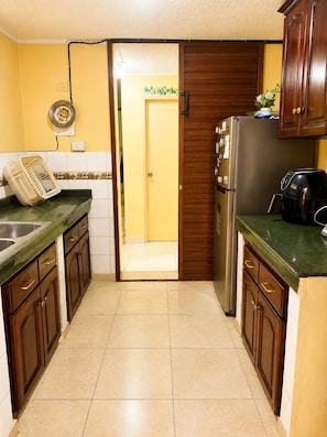 A kitchen with a refrigerator, a coffee maker, and a sink.