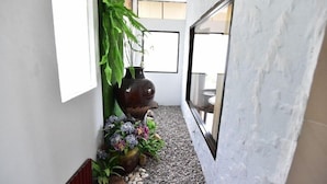 A hallway with a white wall, a large window, and a decorative plant arrangement. - Koh Hai Fantasy Resort and Spa (Ko Lanta)