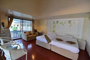 A hotel room with a bed, a sofa, a chair, a balcony, and a wall with a floral design. - Koh Hai Fantasy Resort and Spa (Ko Lanta)