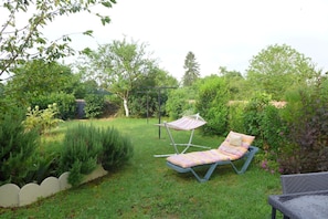 A garden with a grassy lawn, a hammock, and a lounge chair.
