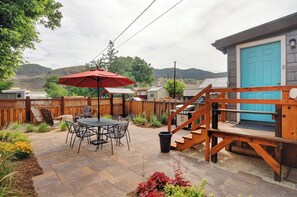 A patio with a table and chairs, a wooden deck, and a blue door. - Prime Location • Fire Pit • Private, Landscaped Backyard (Salida)