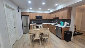 Eine moderne Küche mit Holzschränken, Edelstahlgeräten und einem Essbereich mit Holztisch und -stühlen.
