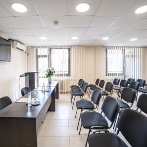 A conference room with a long table, chairs, a plant, and a radiator. - Novi Sad Hotel (Novi Sad)