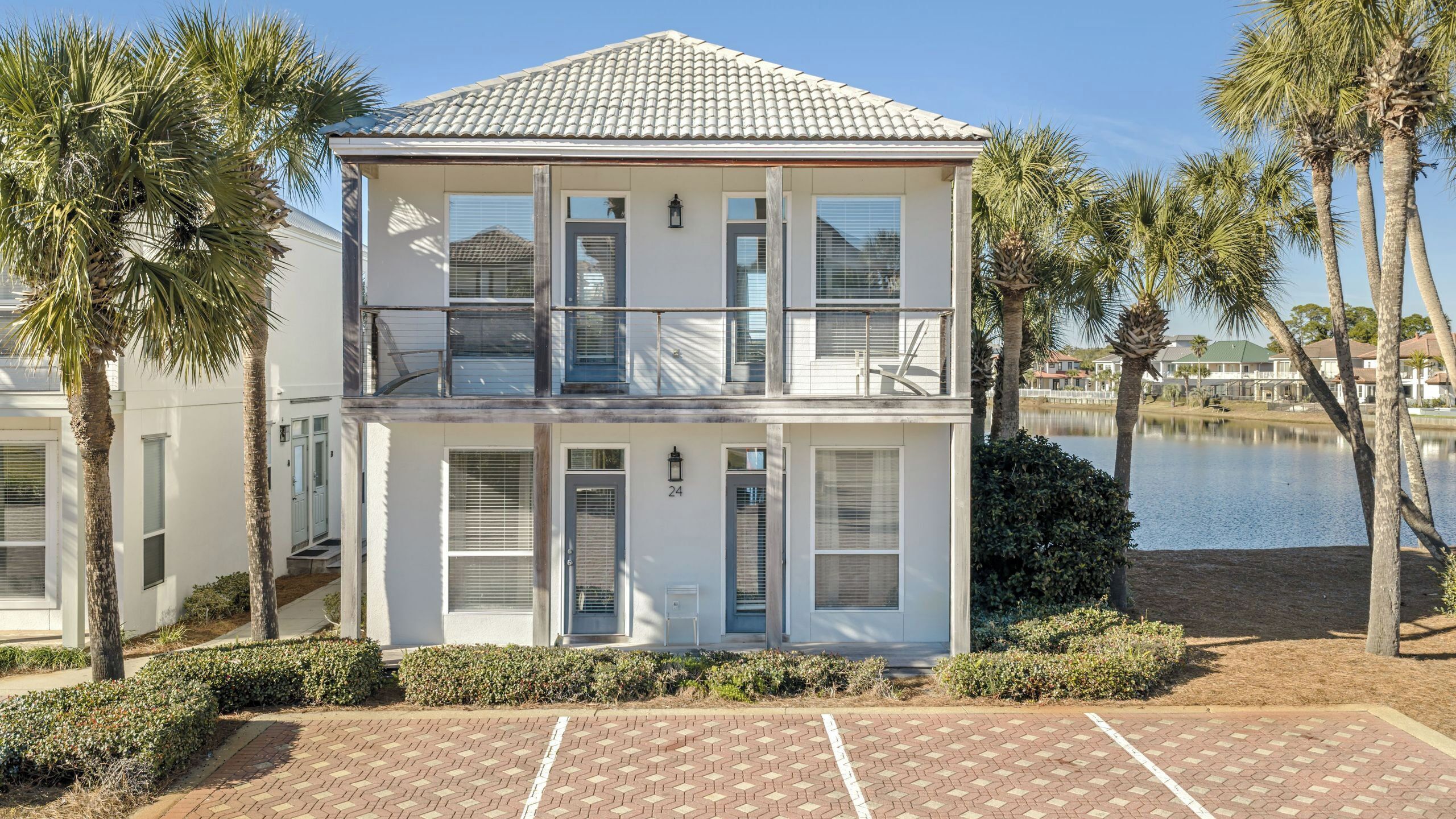 A two-story building with a balcony, large windows, and a view of a body of water.