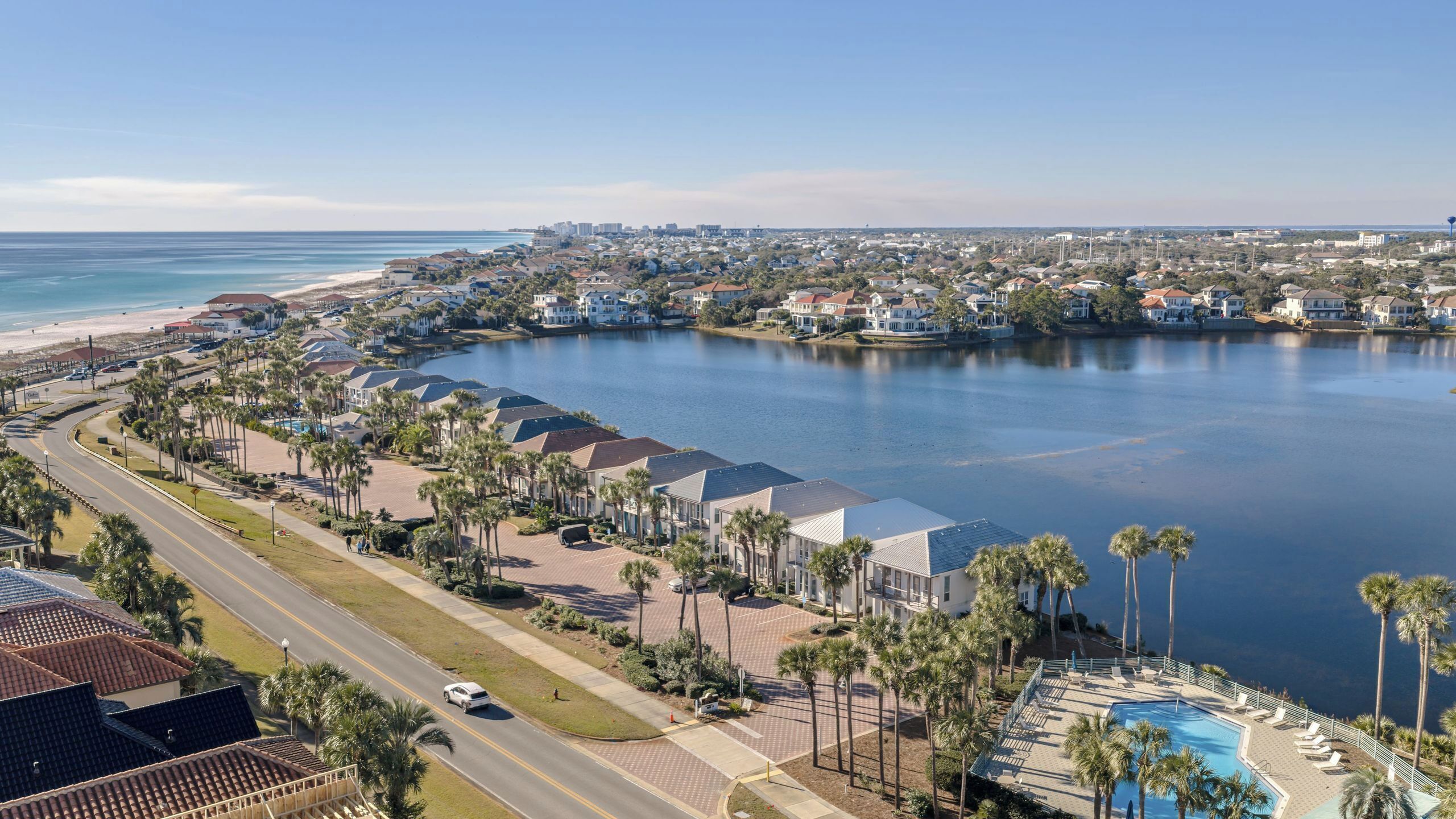 A coastal residential area with a large body of water, houses, and a swimming pool.