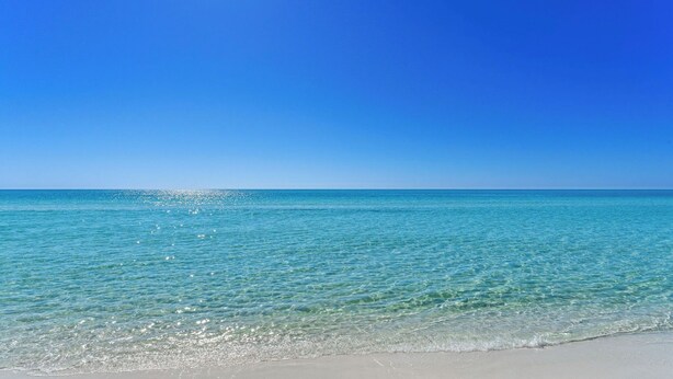 A beach with clear turquoise water and a clear blue sky.