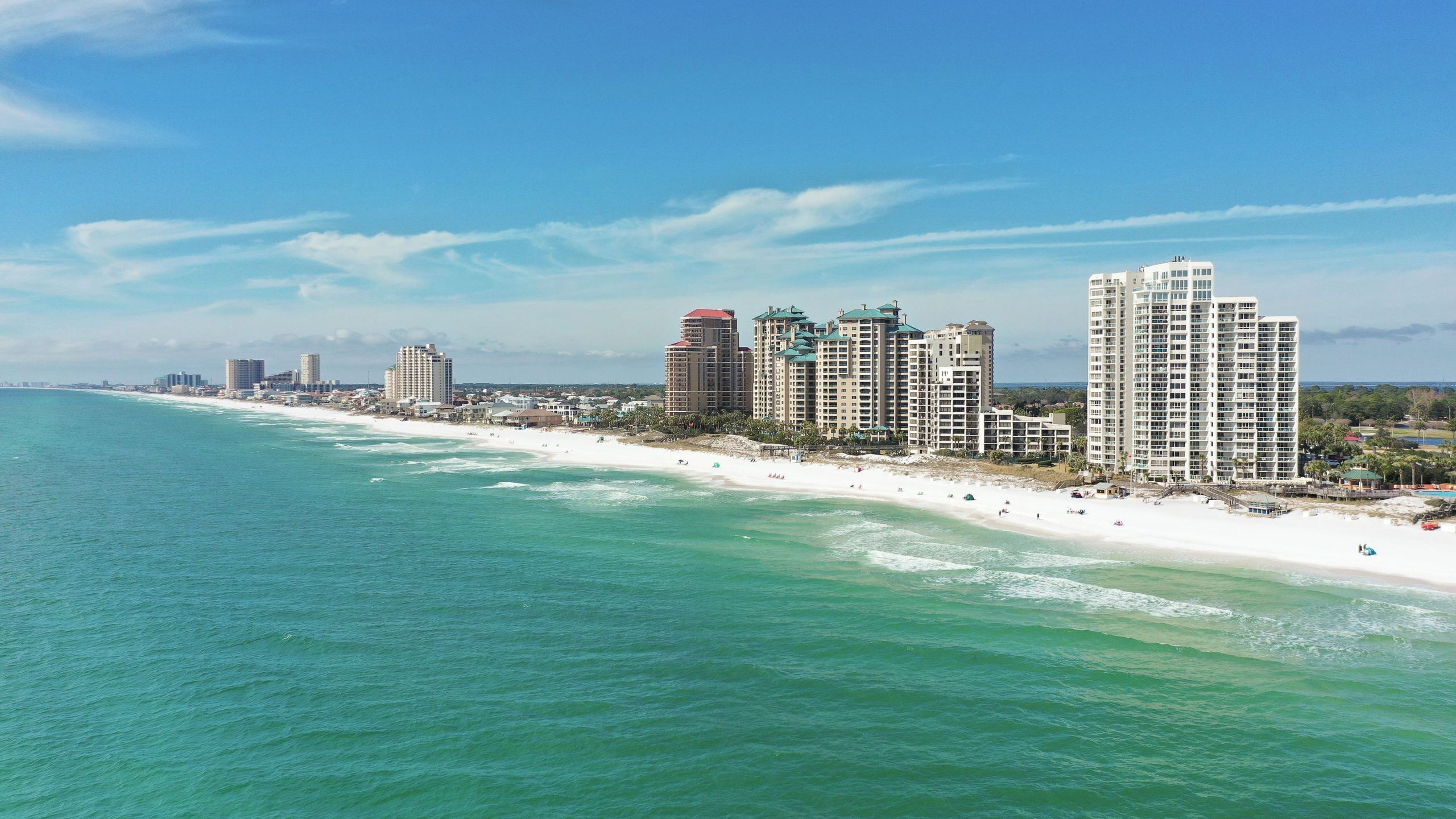 A coastal cityscape with high-rise hotels along a sandy beach.