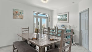A dining room with a wooden table, chairs, and a vase of flowers. - Emerald Breeze by Avantstay Shared Pool + Tennis Court + Balcony Dining + Near Beach and Harbor Boardwalk (Destin)