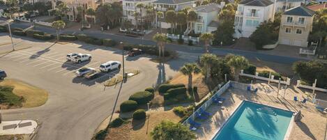 A residential area with a swimming pool, parked vehicles, and houses with balconies.