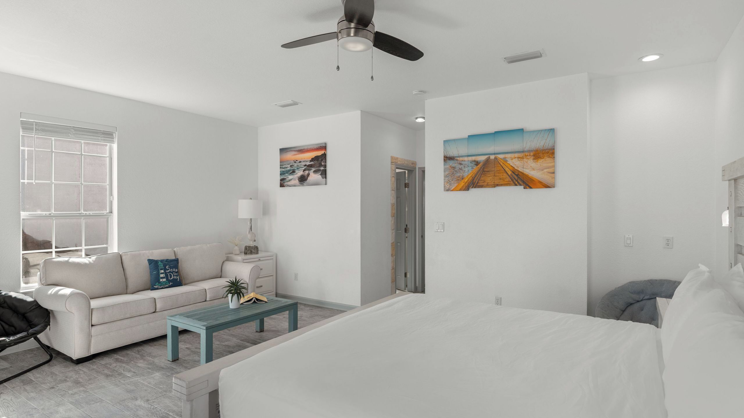A modern hotel room with a bed, a sofa, a coffee table, and artwork on the walls.