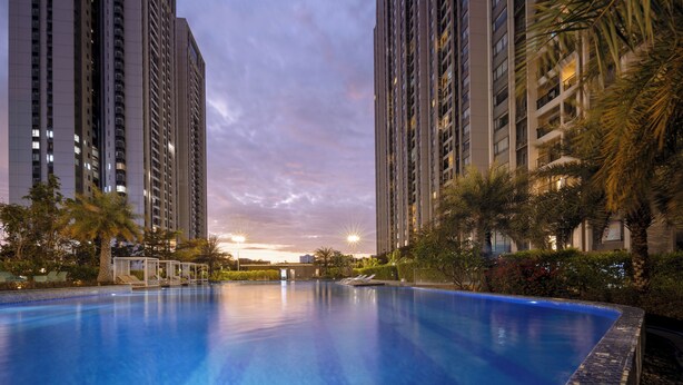 A swimming pool surrounded by tall residential buildings, with a sunset in the background.