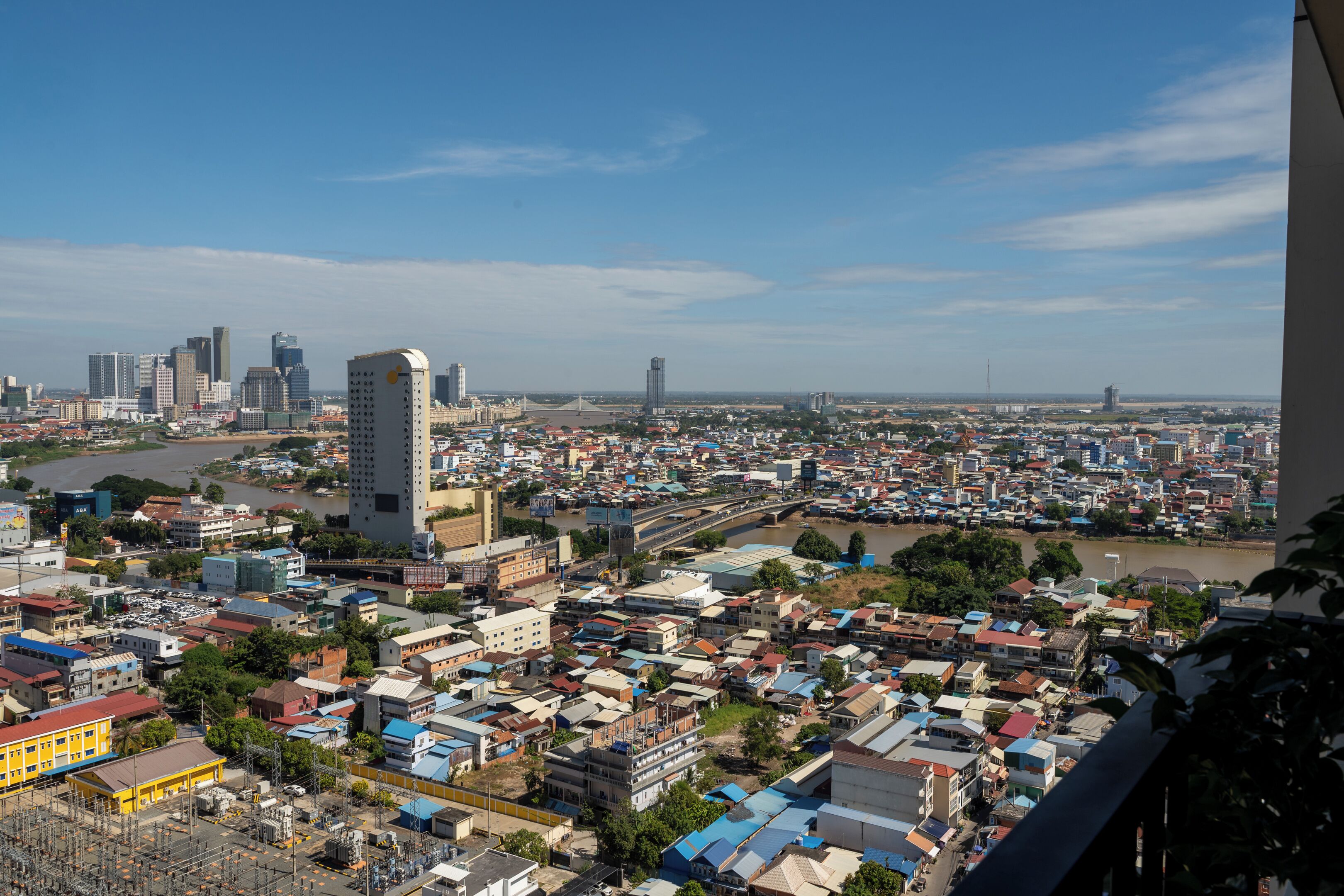 Paisagem urbana com prédios altos e edifícios menores, um rio e uma ponte.