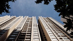 A high-rise building with multiple floors and balconies, viewed from a low angle looking up.
