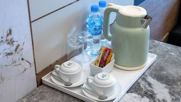 A tray with a teapot, two cups, a jug, and a box of tissues on a marble countertop.