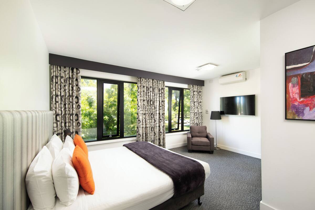 Una habitación de hotel moderna con una cama grande, un sofá, una silla y un televisor.