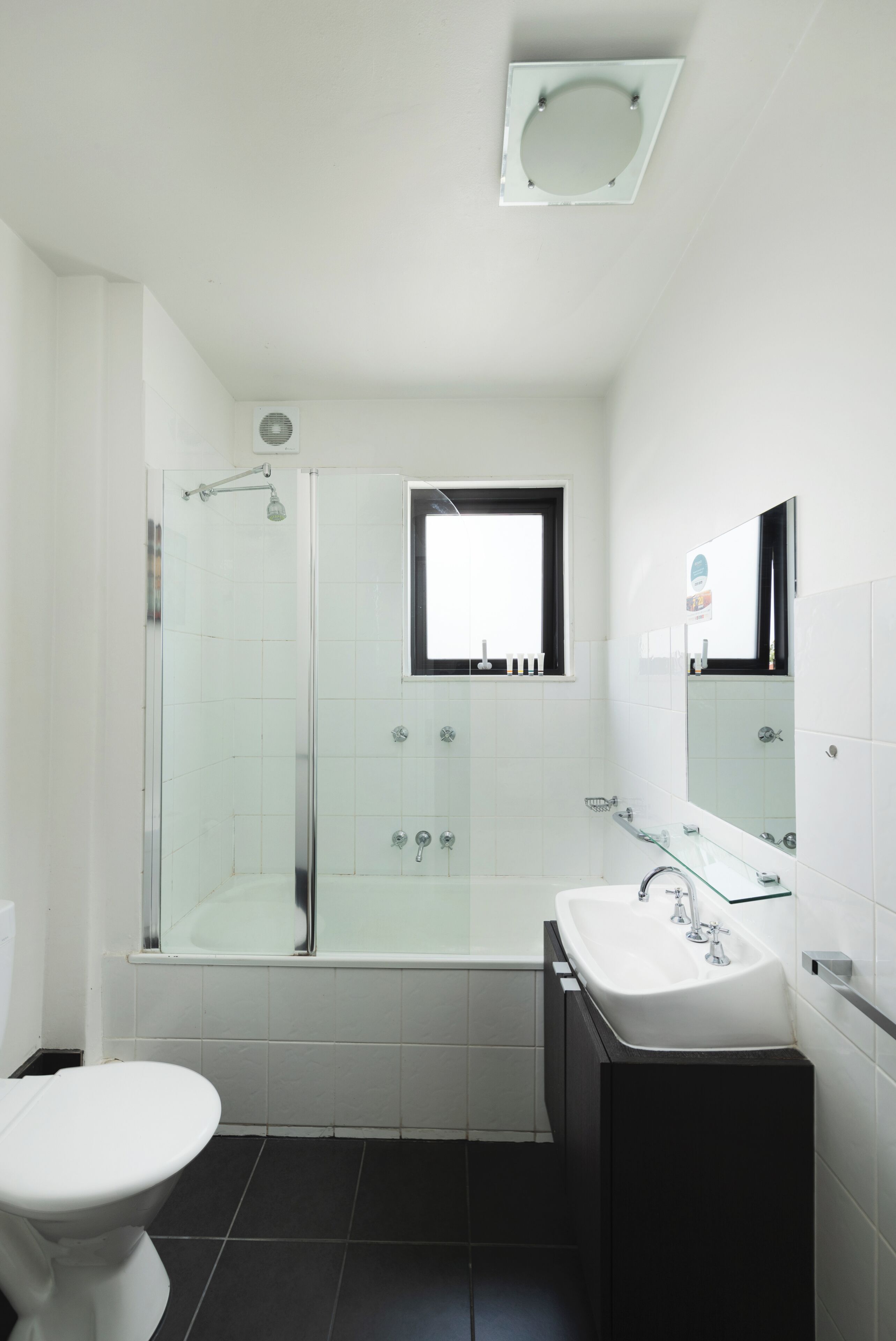 A modern bathroom with a glass-enclosed shower, a white toilet, a sink, and a mirror.