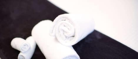 A set of white towels rolled up and placed on a black surface.