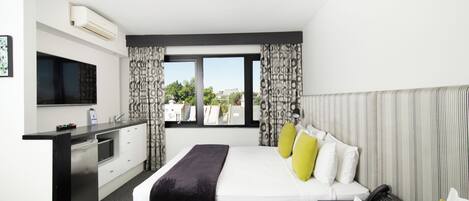 A hotel room with a bed, bedside table, desk, and a TV.