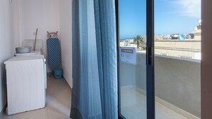 A balcony with a view of a cityscape, a drying rack, a washing machine, and a warning sign. - 3BR Central with Balcony - Sliema Area (Pembroke)