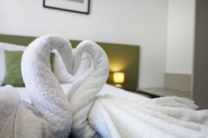 A hotel room with a bed, a green pillow, and a wall-mounted light. - 3BR Central with Balcony - Sliema Area (Pembroke)