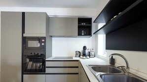 A modern kitchen with a built-in oven, microwave, and a coffee maker. - 3BR Central with Balcony - Sliema Area (Pembroke)