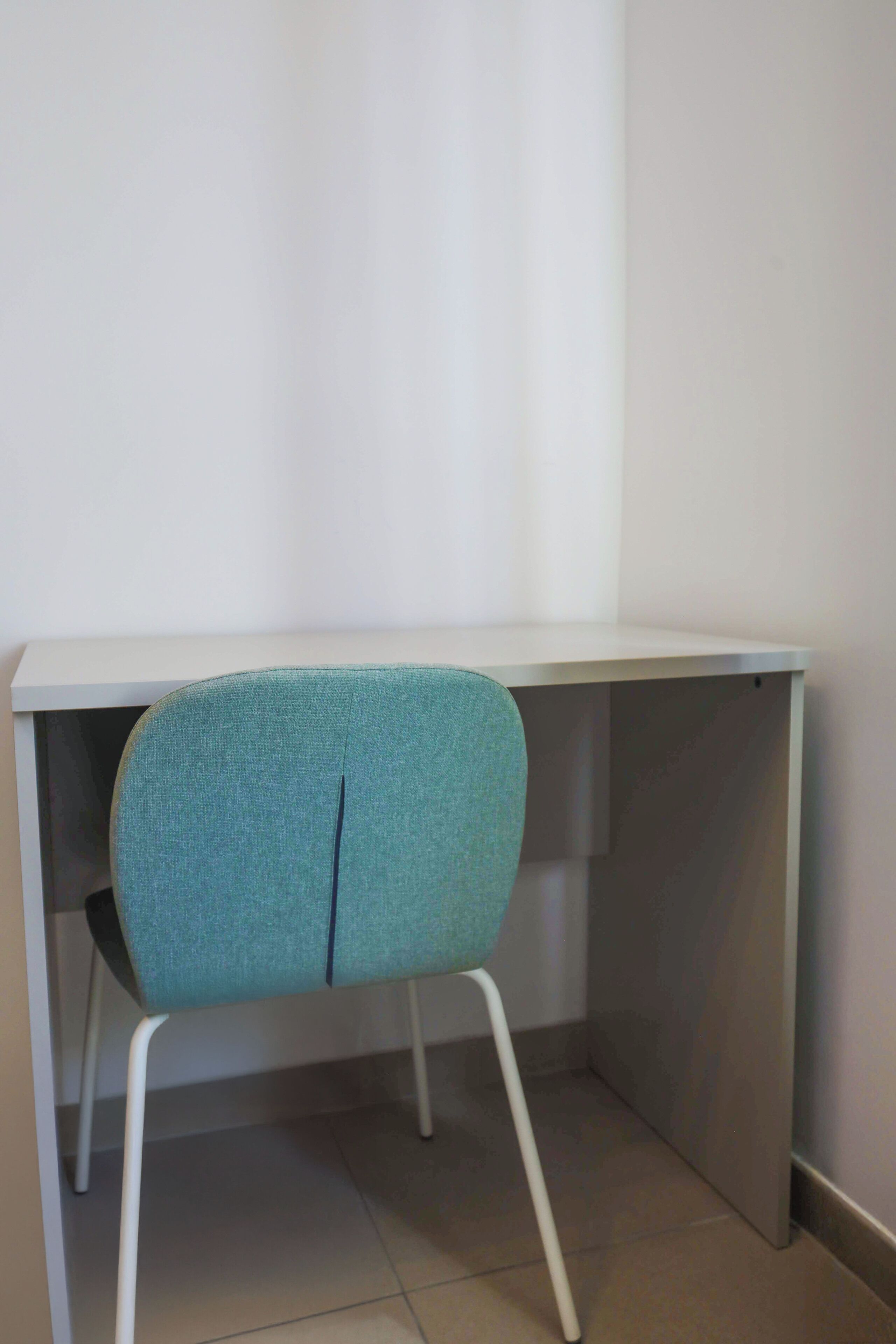 Un bureau d’angle avec une chaise de couleur turquoise.