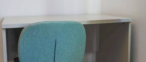 Un bureau d’angle avec une chaise de couleur turquoise.