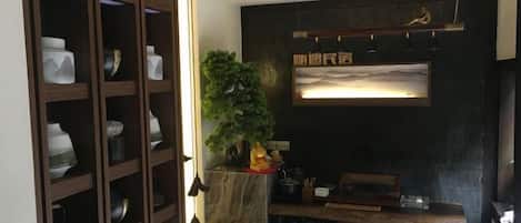 A room with a wooden cabinet, a small table, a plant, and a wall-mounted shelf.