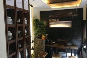 A room with a wooden cabinet, a small table, a plant, and a wall-mounted shelf. - Phoenix Suiyu Riverview Homestay (North Gate Chenglou Branch) (Fenghuang)