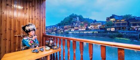A wooden balcony with a view of traditional buildings along a river.