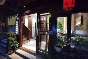 A hotel entrance with a wooden staircase leading inside, potted plants, and a sign indicating the hotel's name. - Phoenix Suiyu Riverview Homestay (North Gate Chenglou Branch) (Fenghuang)