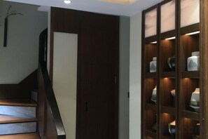 A staircase leading to a dark wooden door, a glass-fronted cabinet with decorative items, and a wall-mounted light fixture. - Phoenix Suiyu Riverview Homestay (North Gate Chenglou Branch) (Fenghuang)