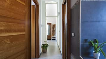 A hallway with wooden doors, a potted plant, and a tiled wall.