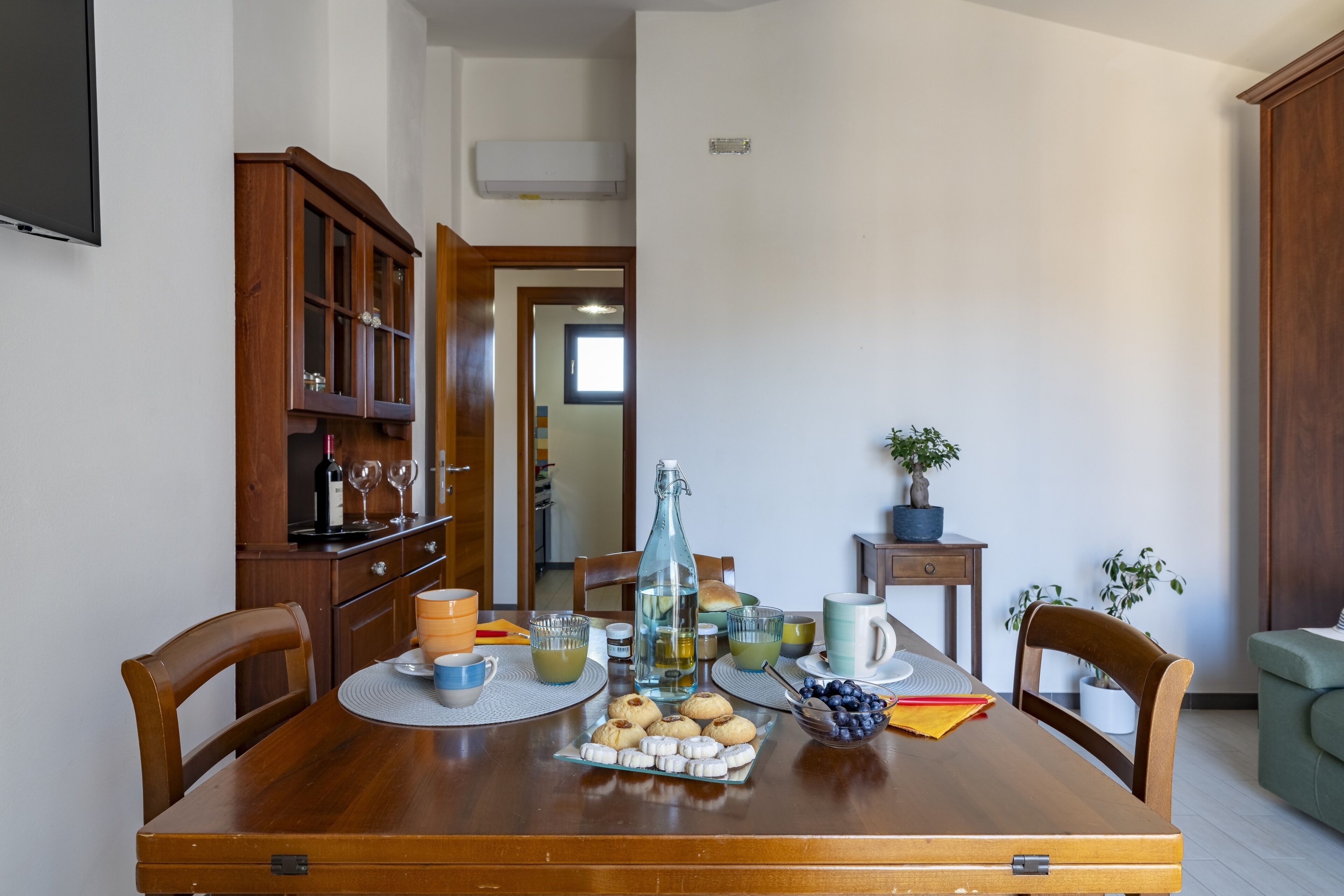 A dining table set with various items including a bottle, glasses, and a plate of cookies.