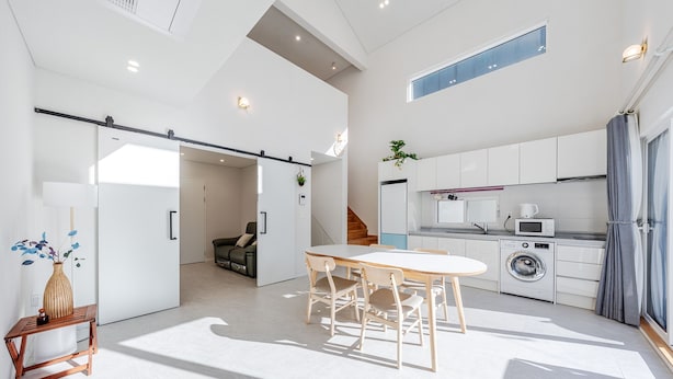 Een moderne keuken met witte kasten, een magnetron en een wasmachine.