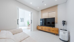 Een moderne woonkamer met een grote flatscreen televisie, een houten kast en een witte luchtreiniger.