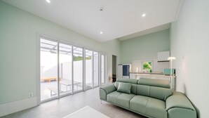 En moderne stue med sofa, spiseplads og en skydedør til et udendørs område.