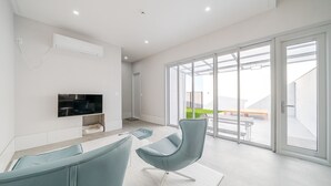 En moderne stue med et fladskærms-tv, en sofa og et spiseområde med et bord og stole.
