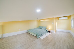 Een slaapkamer met een bed, nachtkastje, lamp en raam.