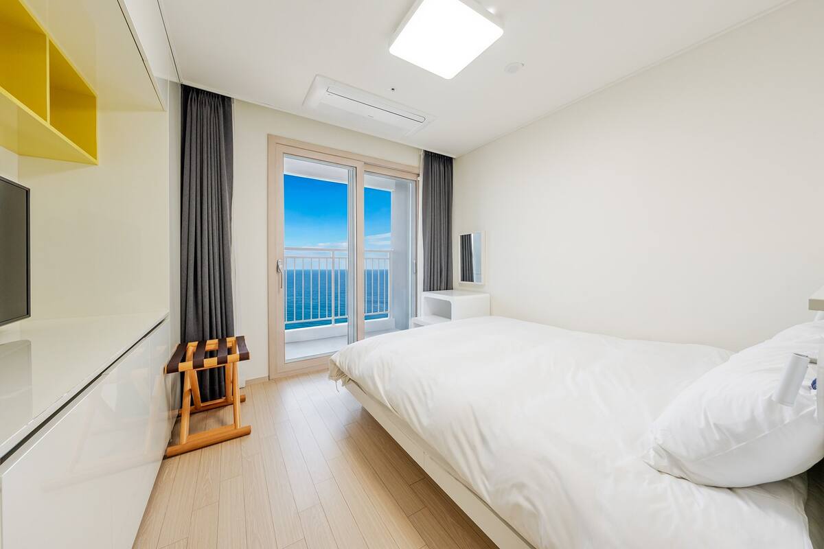 Et hotelværelse med en seng, et fjernsyn, et lille bord og en balkon med udsigt.