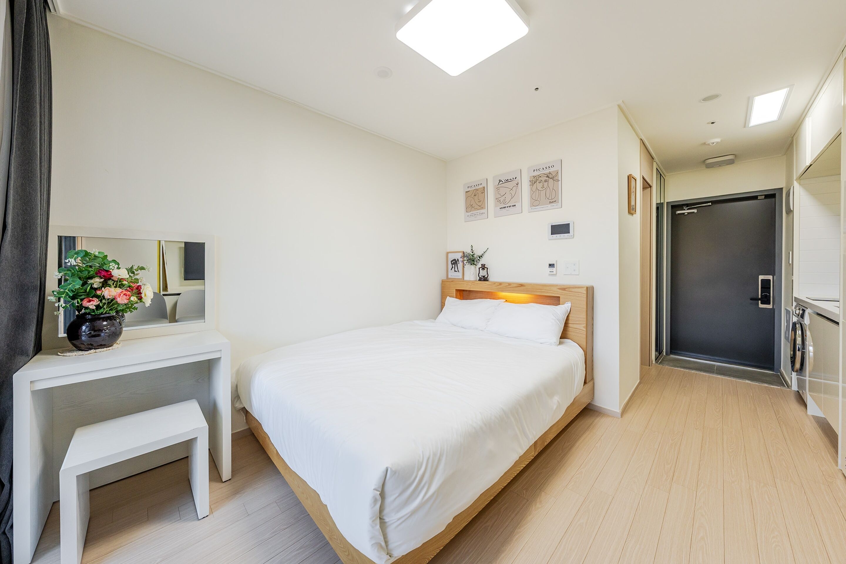 Une chambre d’hôtel comprenant un lit, un bureau avec un miroir, un banc et une porte donnant accès à une salle de bain.