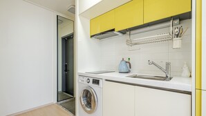 A compact kitchen with a washing machine, a sink, and a coffee maker. - Yangyang Oceanstay 24K (Yangyang)