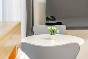 A modern room with a round white table, a grey chair, and a small potted plant with yellow flowers. - Yangyang Oceanstay 24K (Yangyang)